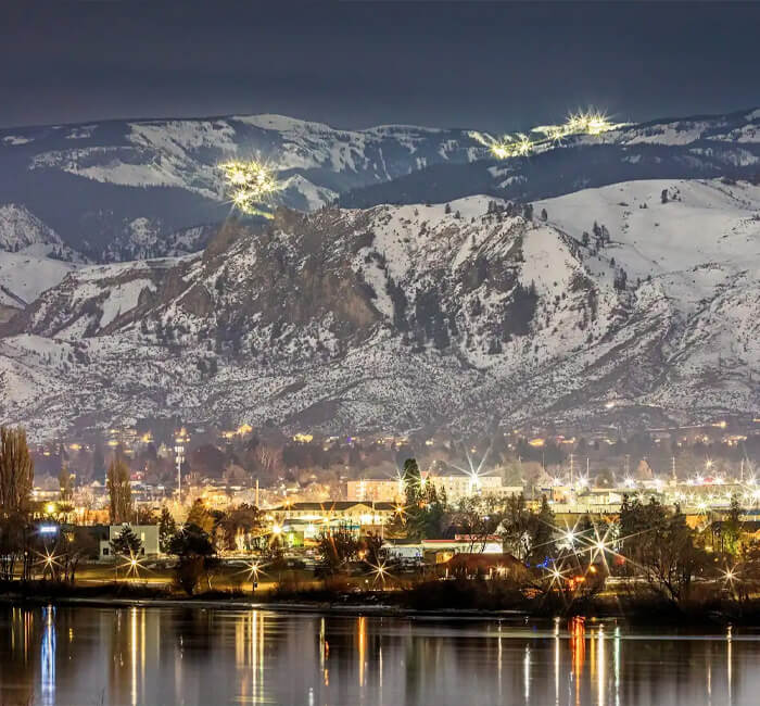 Night photo of downtown Wenatchee across the river and night skiing lights of Mission Ridge in the mountains above,