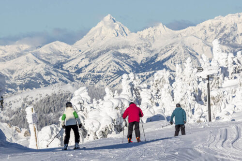 Three skiers starting from the top on fresh groomed run